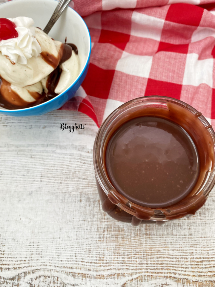 hot fudge in jar with bowl of ice cream in background