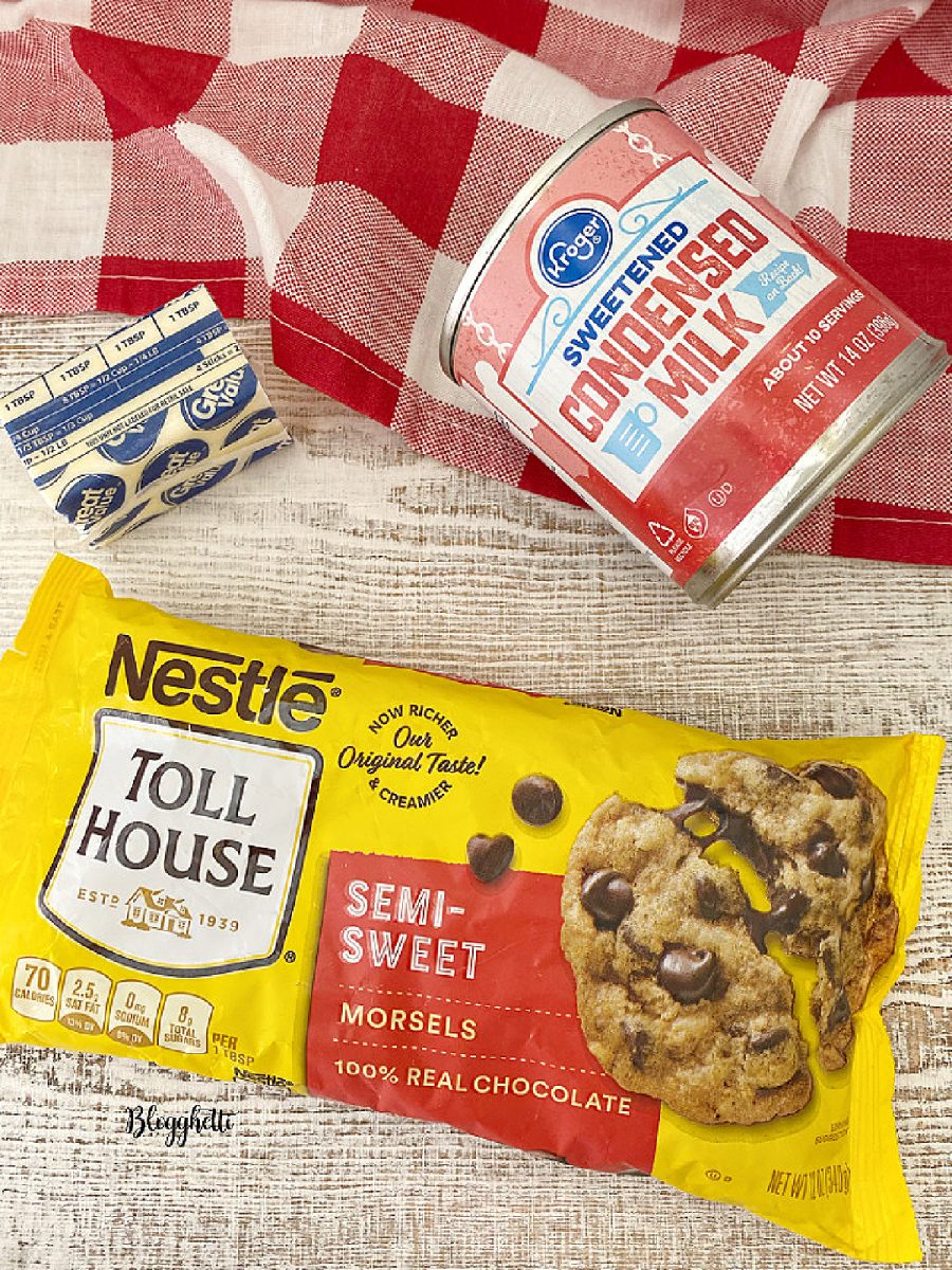 Top-down view of Nestle Toll House semi-sweet morsels, Kroger sweetened condensed milk, and sticks of butter on a table.