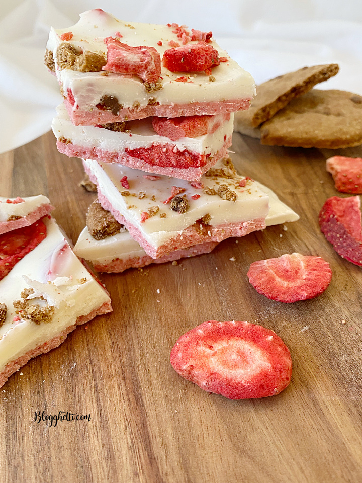 squares of strawberry candy bark stacked on wooden board