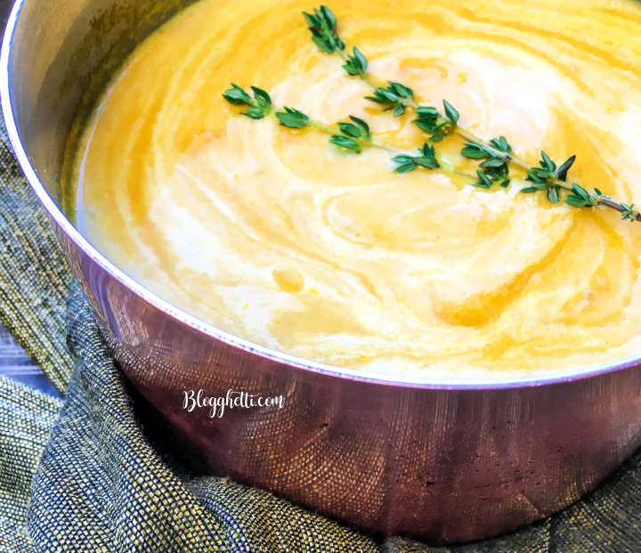 delicious bowl of carrot ginger soup with thyme sprig