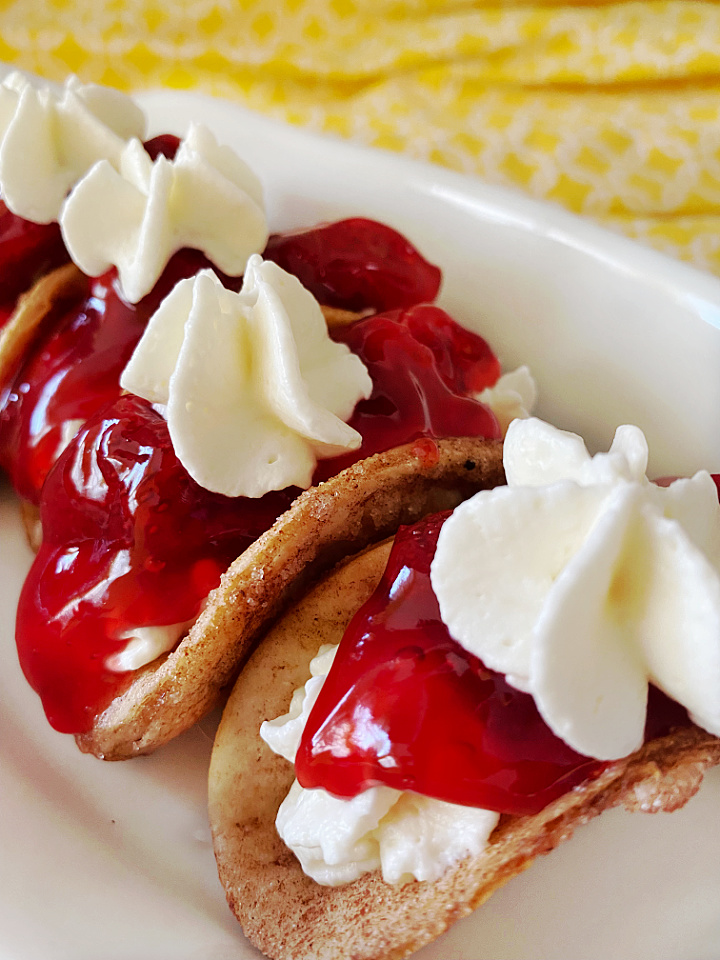 close up of strawberry cheesecake tacos on white platter