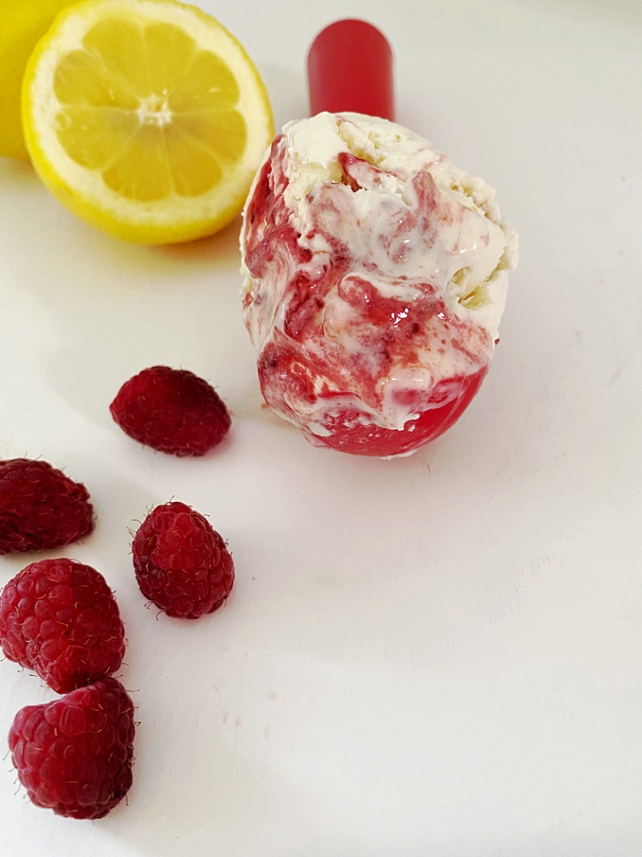 scoop of lemon raspberry ice cream with fruit in background