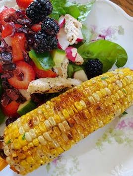 roasted corn on the cob with plate of salad