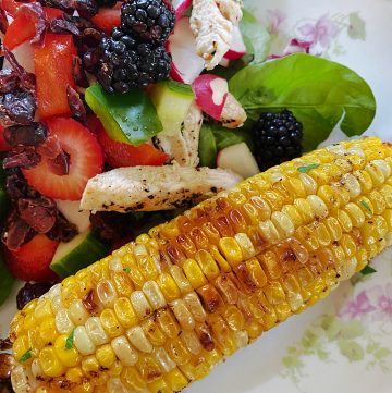 roasted corn on the cob with plate of salad