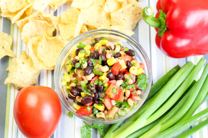 Cowboy Caviar in bowl surrounded by fresh veggies and chips