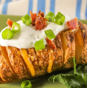 loaded hasselback potato close up on green plate