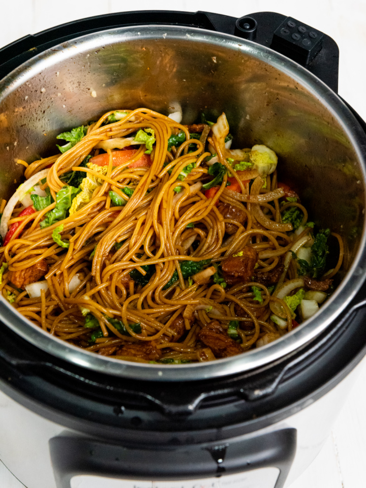 stirring the cooked pork lo mein in the Instant Pot and ready to serve