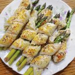 baked puff pastry wrapped asparagus on white plate