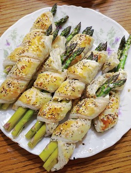 baked puff pastry wrapped asparagus on white plate