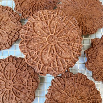 mint chocolate pizzelles stacked on cooling rack