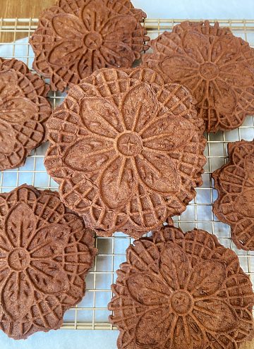 mint chocolate pizzelles stacked on cooling rack