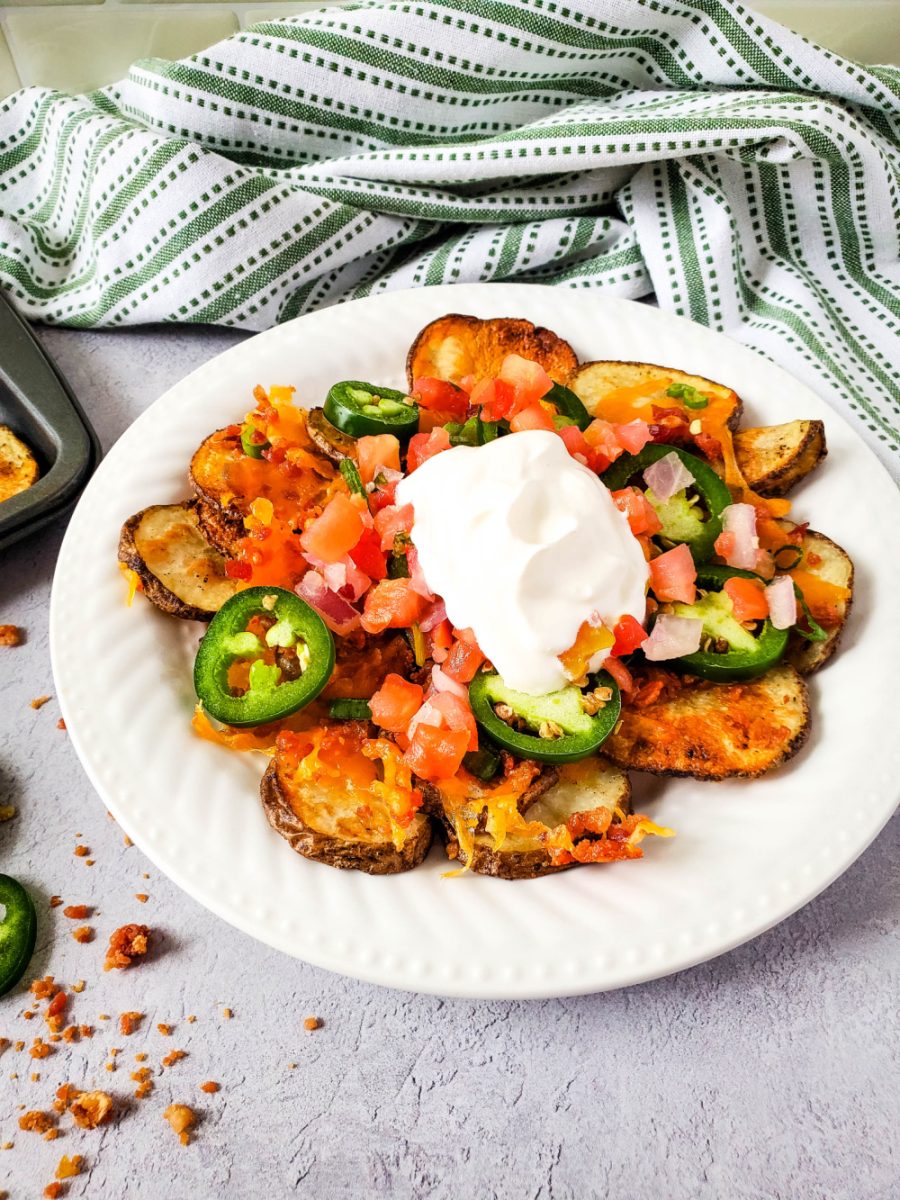loaded Irish Potato Nachos on white plate with green striped towel in background