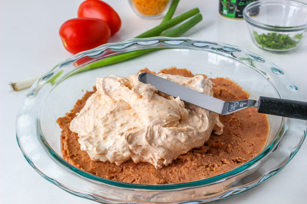 spreading cream cheese layer on refried beans