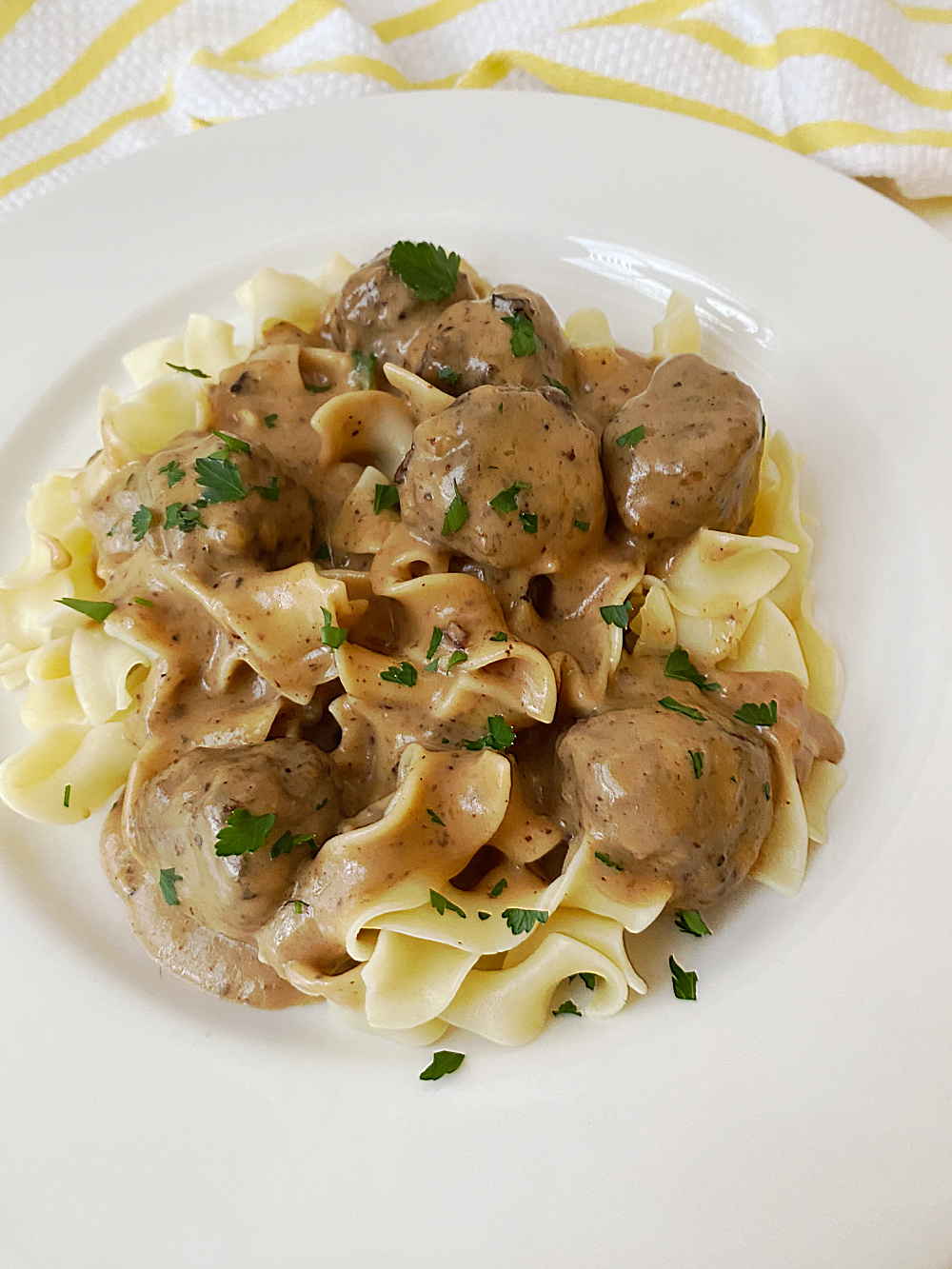 close up of classic Swedish meatballs over noodle in white bowl