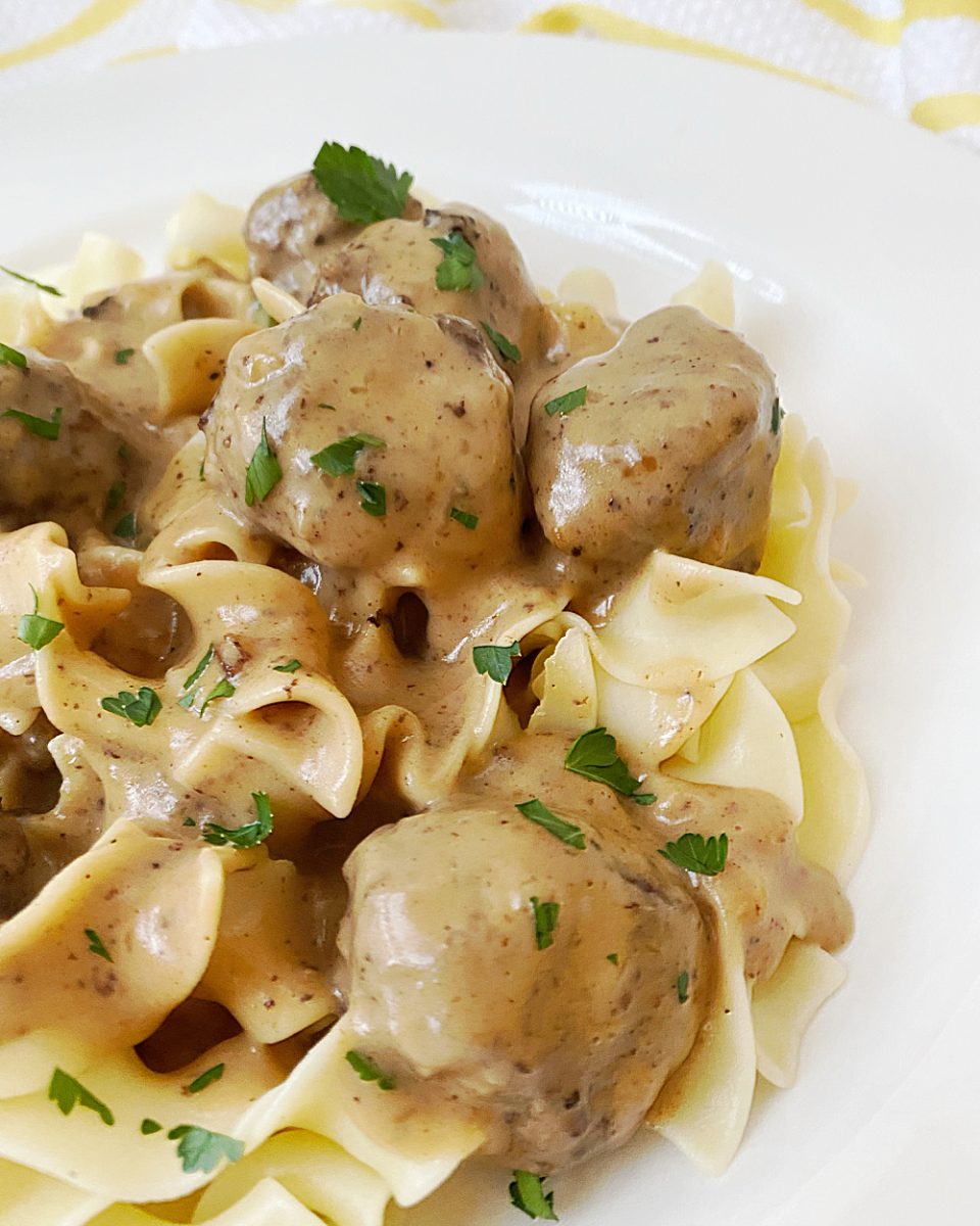 creamy sauce with meatballs flavored with allspice over pasta in bowl