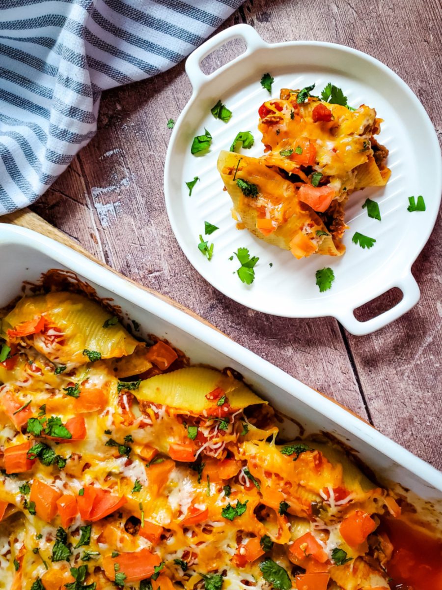 taco stuffed shells in casserole dish with a serving of pasta on plate