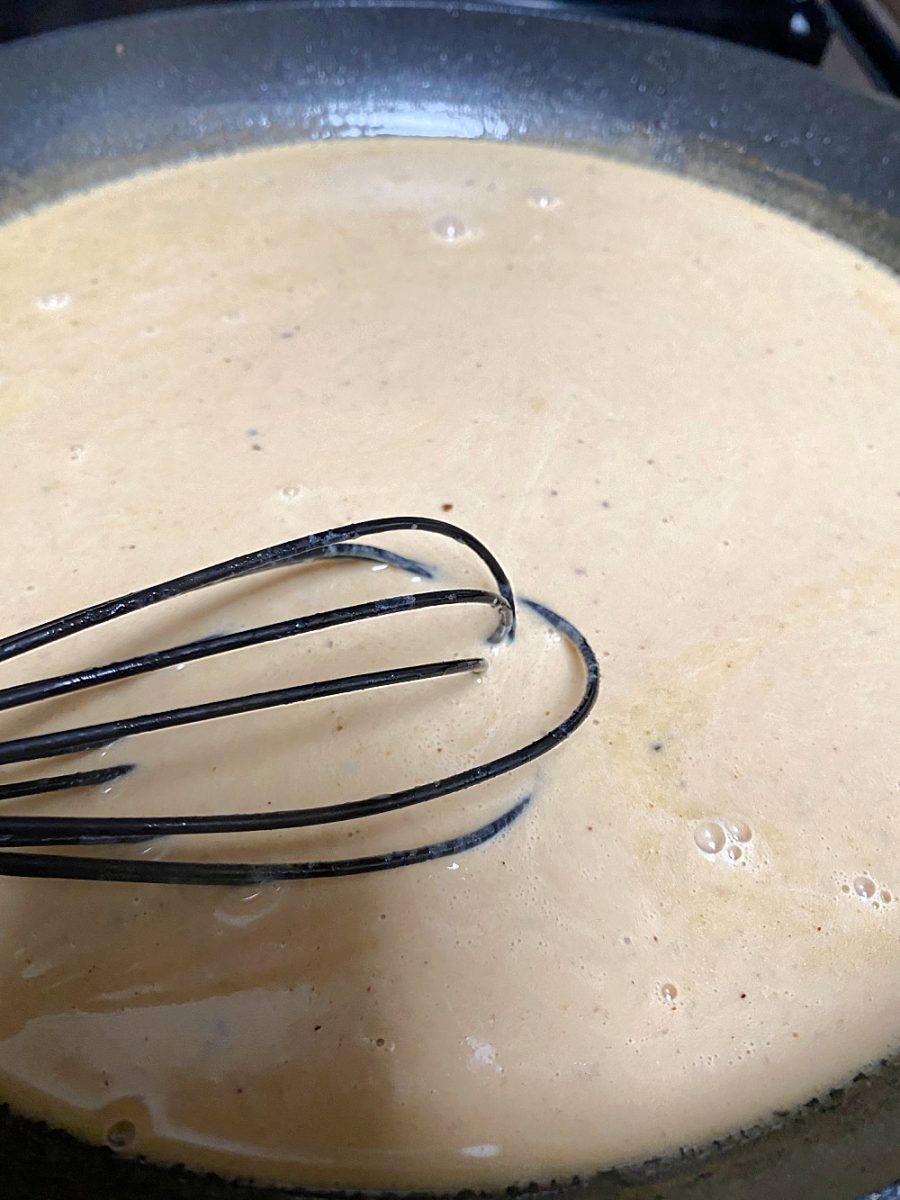 whisking the cream sauce for Swedish meatballs in large skillet
