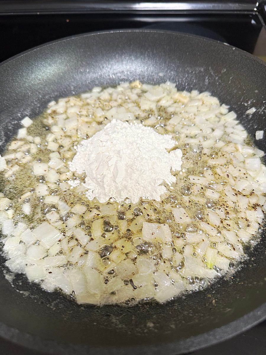 adding flour to onion mixture in skillet to make a roux