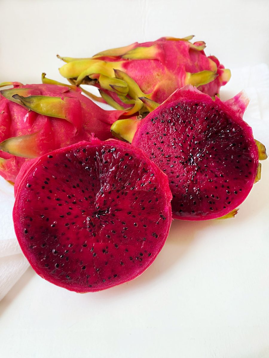 dragon fruit cut in half with a couple of the fruit behind it