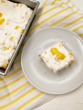 overhead shot of slice of mango coconut cake on white plate and yellow towel