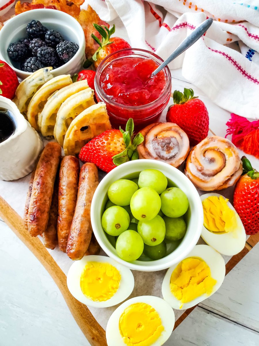 breakfast or brunch board featuring hard boiled eggs, waffles, meat, and fruit
