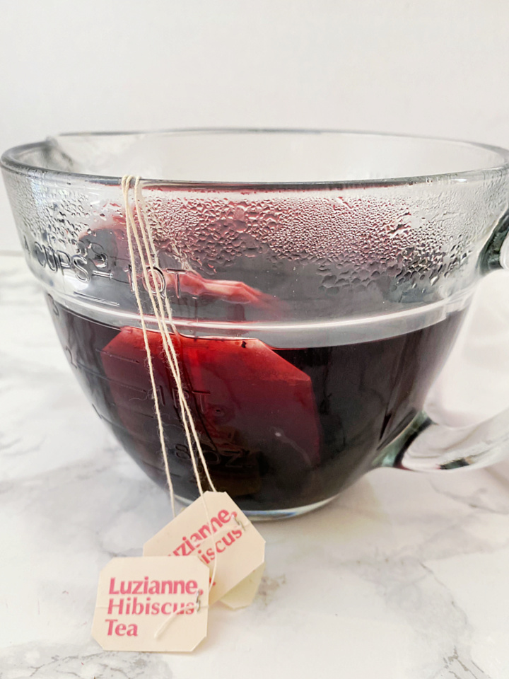 steeping hibiscus tea in glass measuring cup