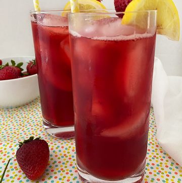 two glasses of strawberry hibiscus tea with straws and fruit garnish