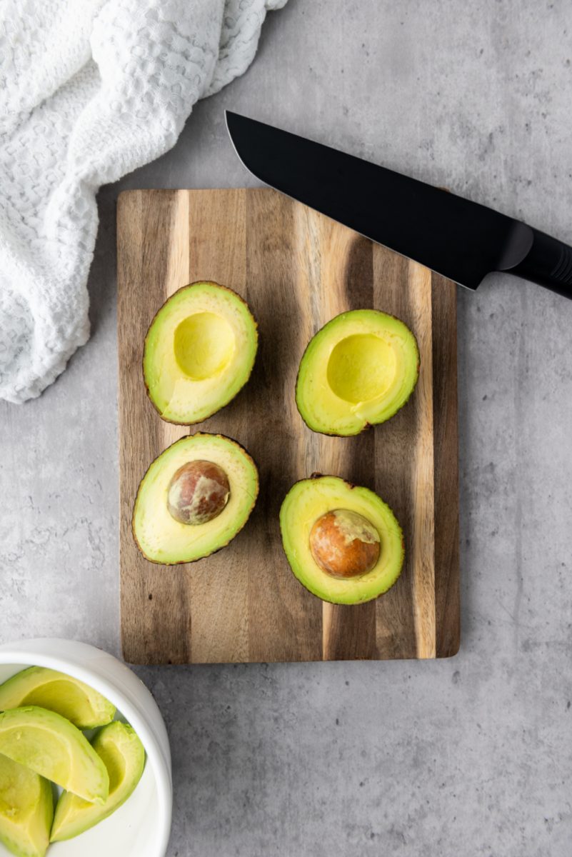 cutting board with avocados cut in half