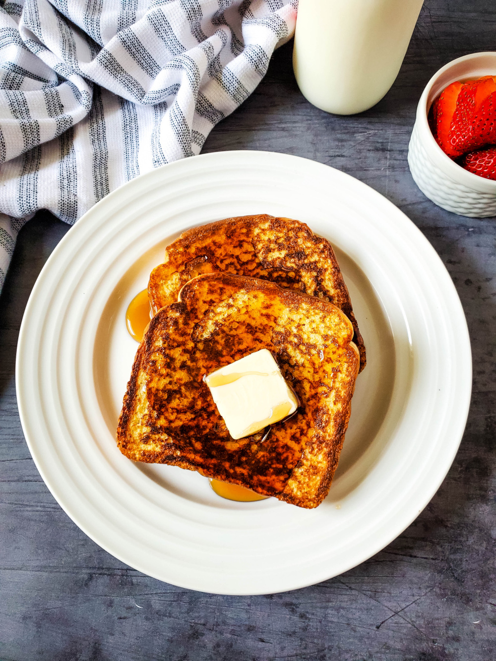 Cinnamon French toast slices with butter and syrup on white plate