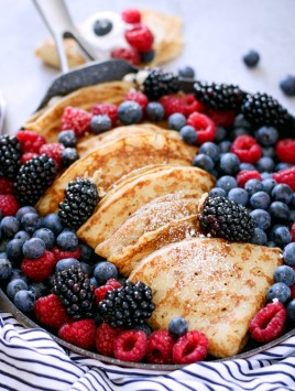 close up of homemade crepes with fresh fruit served from a large skillet
