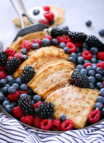 close up of homemade crepes with fresh fruit served from a large skillet