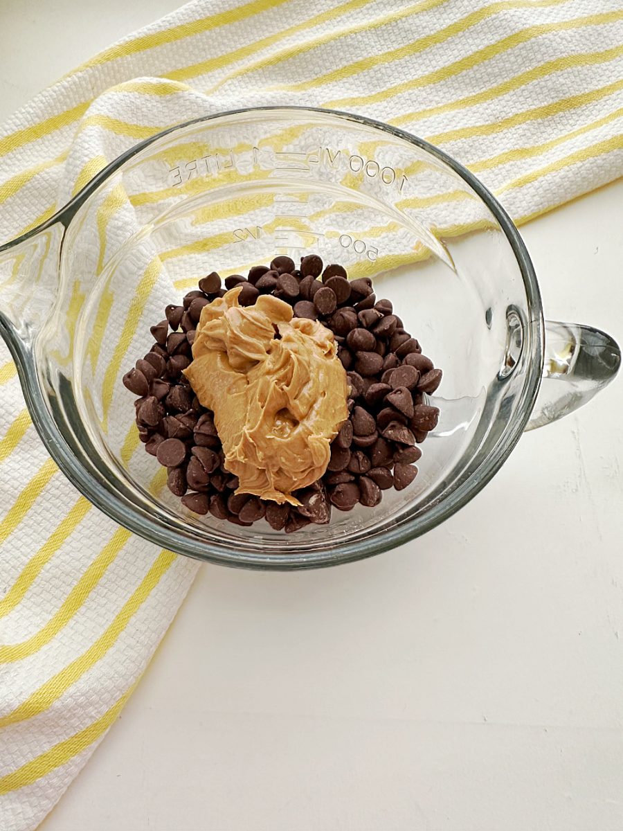glass bowl with peanut butter and chocolate chips ready to melt