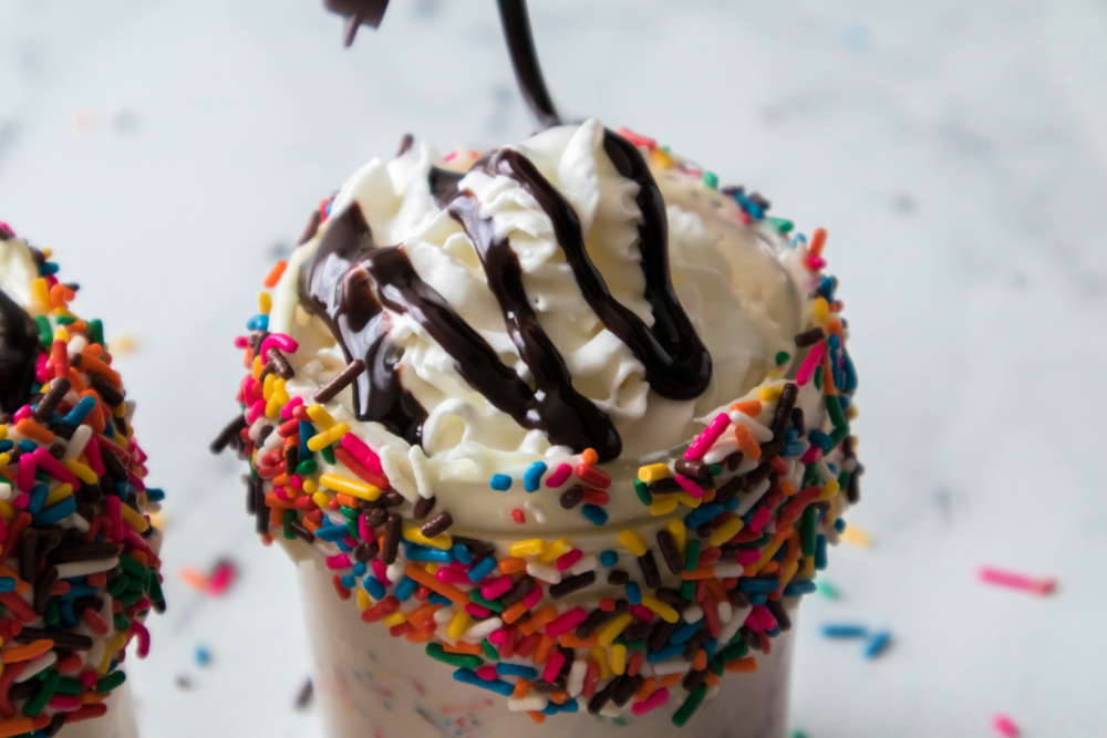drizzle chocolate syrup over whipped cream on milkshake