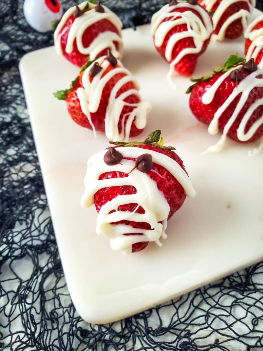 Strawberry mummies on white plate with halloween decor