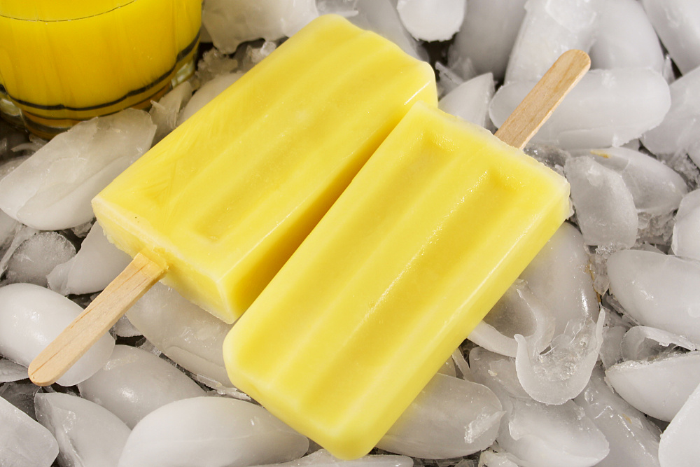 two orange creamsicles on top of ice cubes