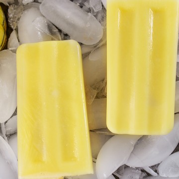 two orange creamsicles with wooden sticks