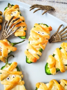 Mummy Jalapeno Poppers with skeleton hands on white tray