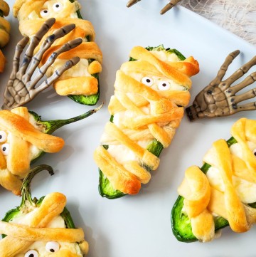 Mummy Jalapeno Poppers with skeleton hands on white tray