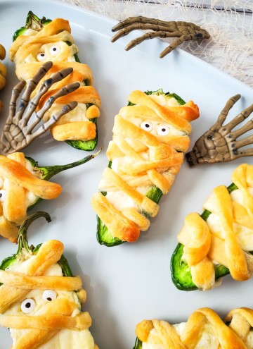 Mummy Jalapeno Poppers with skeleton hands on white tray