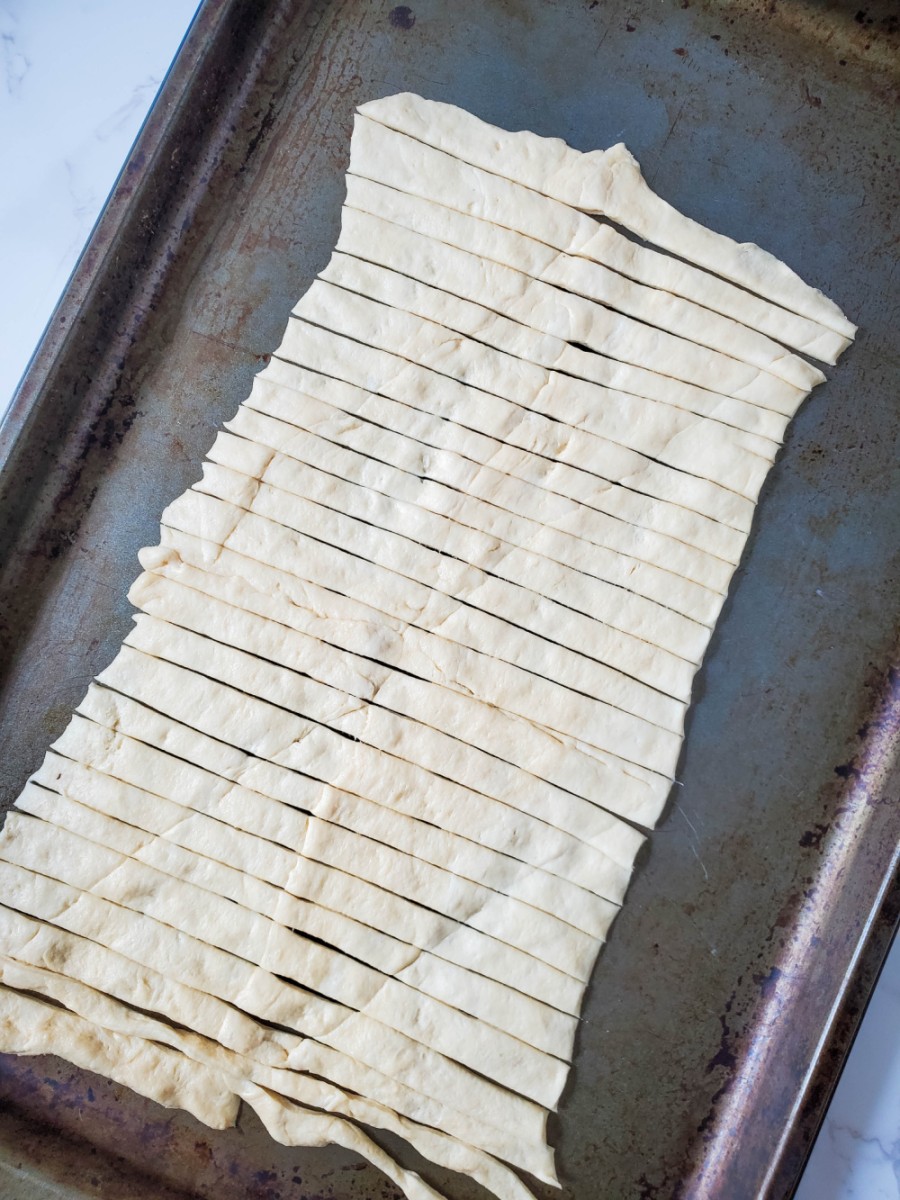 cut crescent roll dough into strips on baking sheet