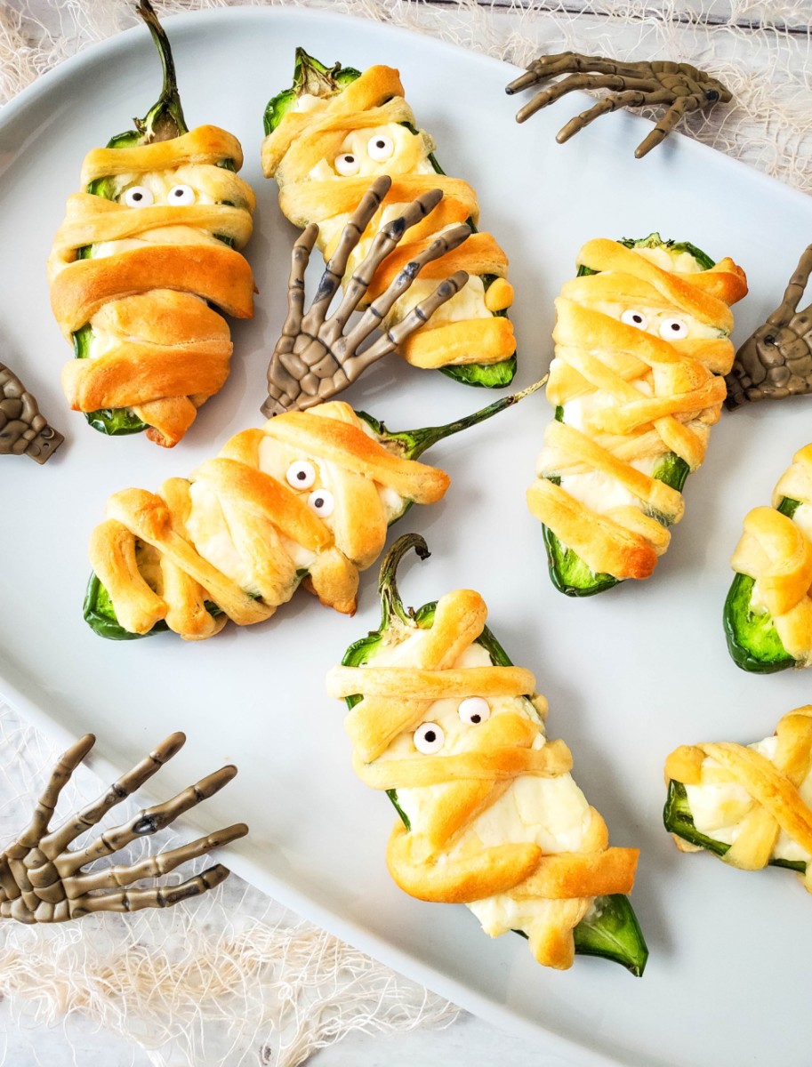 jalapeno poppers wrapped like mummies on white platter