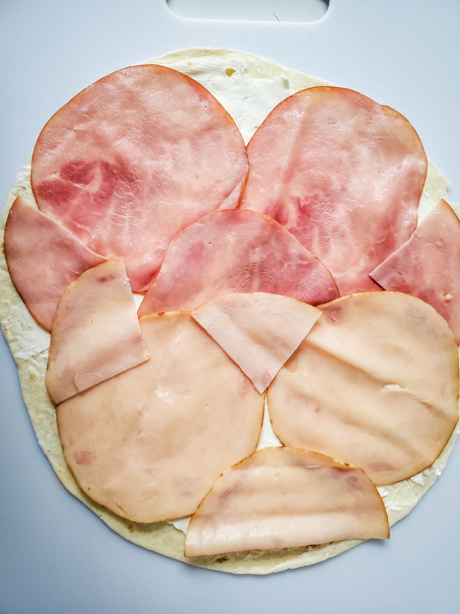 layer ham and turkey slices on tortilla shell
