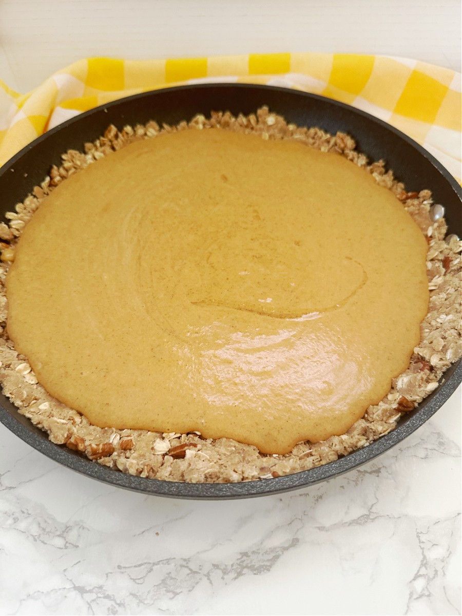 pouring pumpkin filling into crust to bake