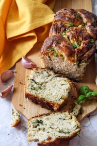 sliced garlic herb bread on wooden board with yellow towel