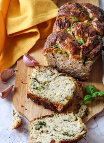 sliced garlic herb bread on wooden board with yellow towel