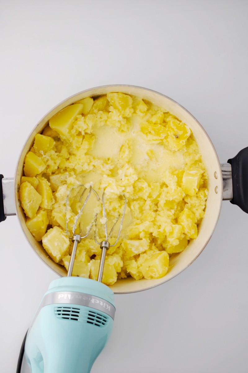 using hand mixer blend potatoes and cream in pot