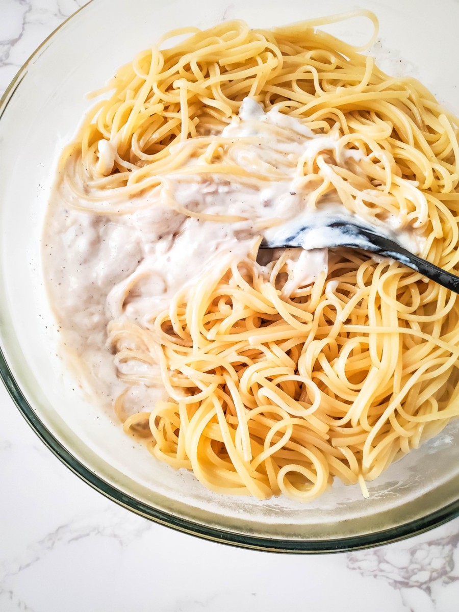 adding spaghetti noodles to creamy turkey sauce in bowl