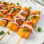 close up of loaded tator tot skewers with sour cream