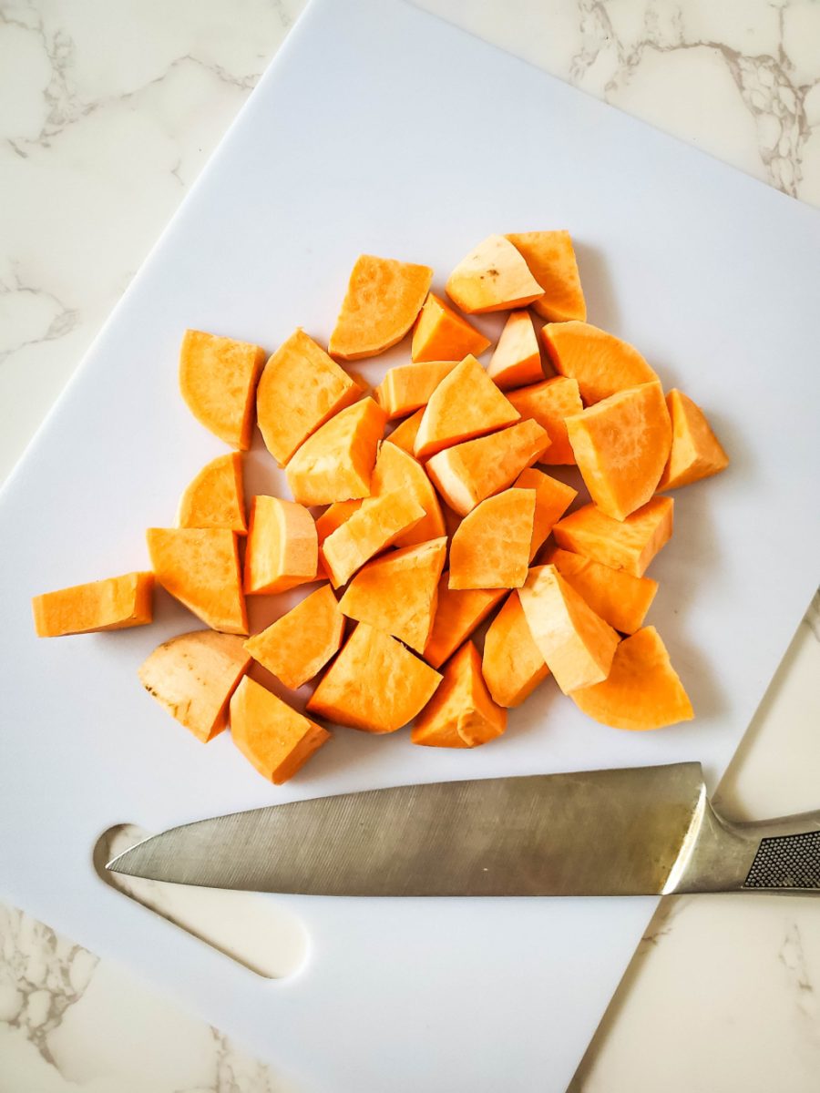 dicing sweet potato with knife on cutting board