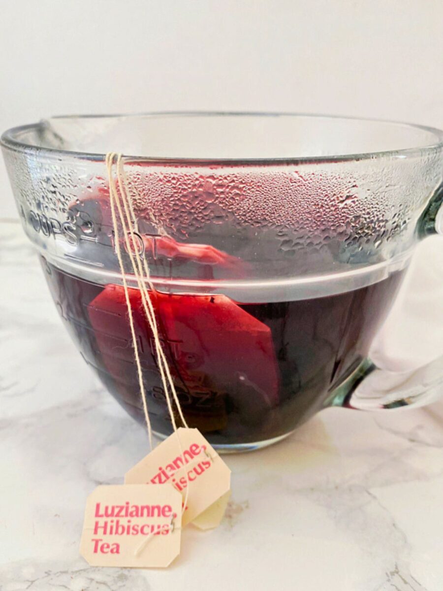 Glass measuring cup with hibiscus tea bags steeping in hot water to make the tea base for Strawberry Hibiscus Iced Tea.